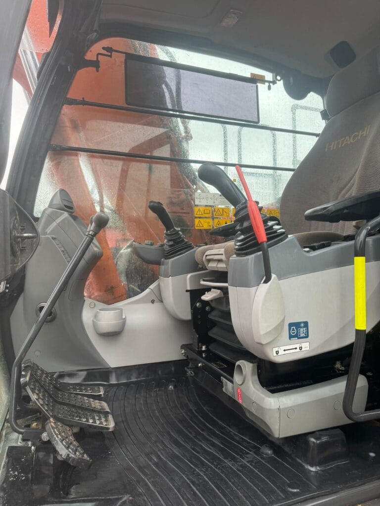 Excavator cabin interior with controls and pedals