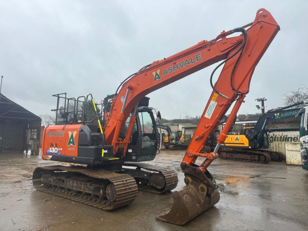 Orange excavator parked on wet construction site